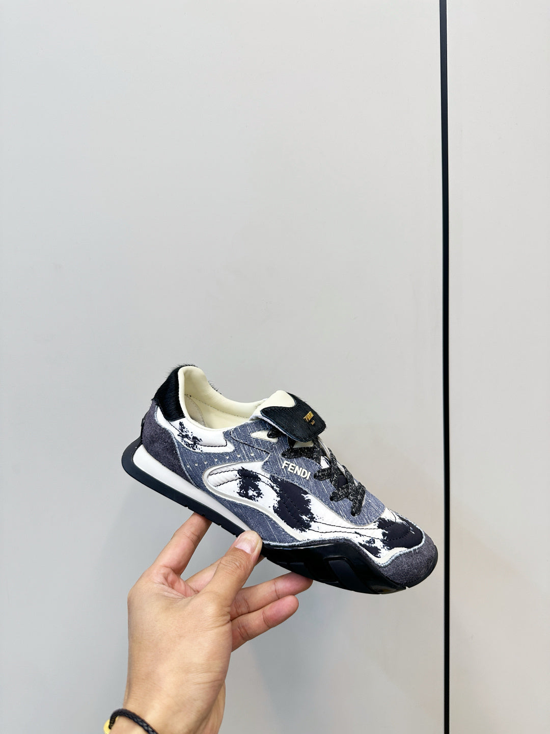 Fendi unisex sneaker held in hand, navy and white graphic upper with black outsole