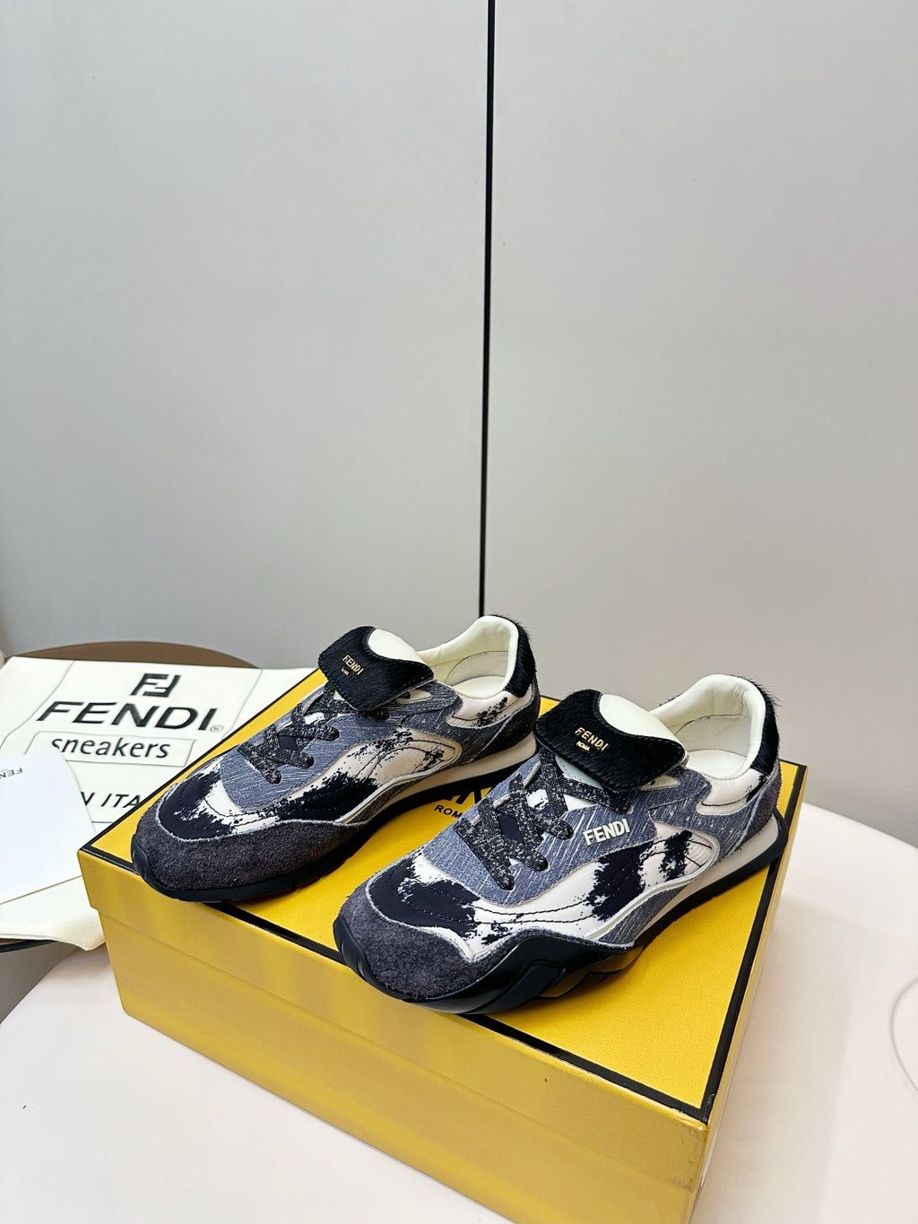 Fendi unisex sneakers on yellow box, navy and white graphic print with black trim