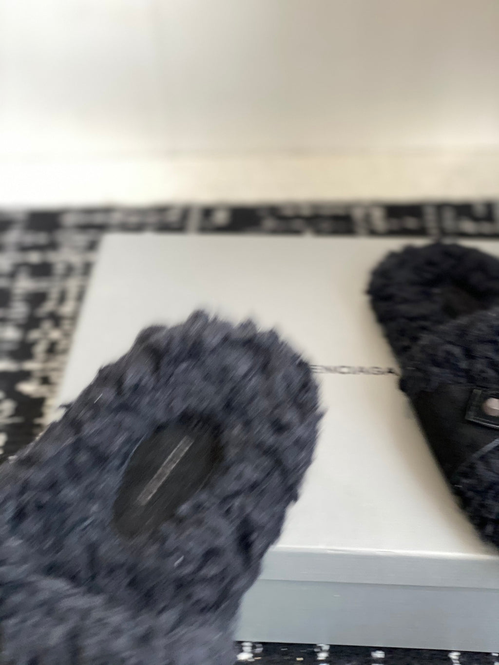 Black fuzzy slide sandals, partial close-up on the box
