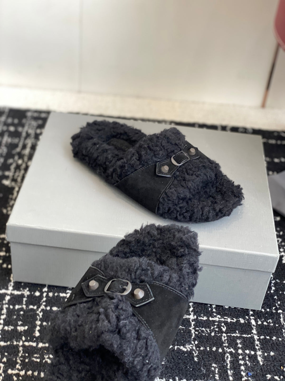 Black fuzzy slide sandal pair with silver buckle details on straps