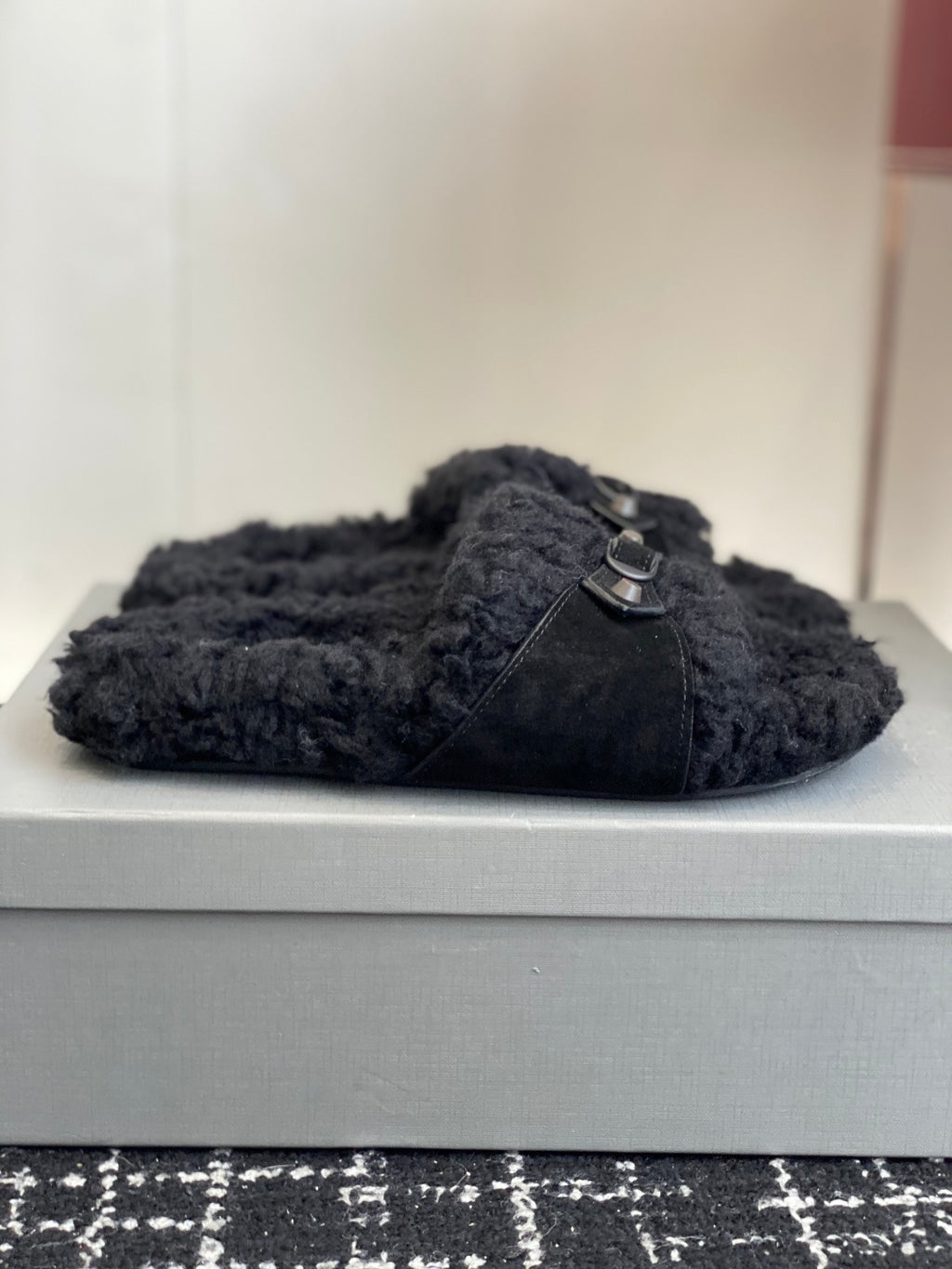 Black fuzzy slide sandal with a single silver buckle strap on the upper