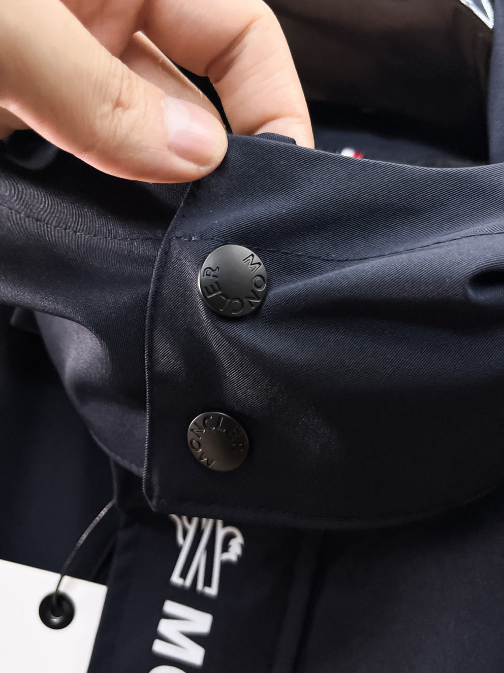 Navy Moncler jacket pocket flap with snap button and logo detail
