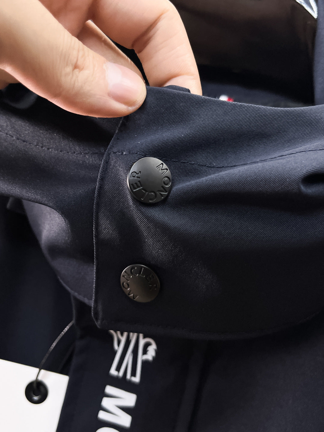 Navy Moncler jacket pocket flap with snap button and logo detail