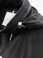 Moncler jacket front close-up with black zipper and snap, logo label visible
