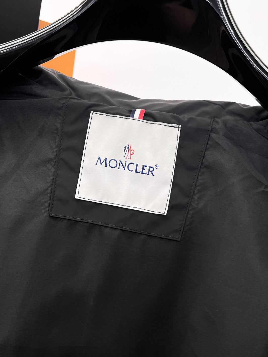 Moncler logo patch on black jacket chest, multicolor stripe accent