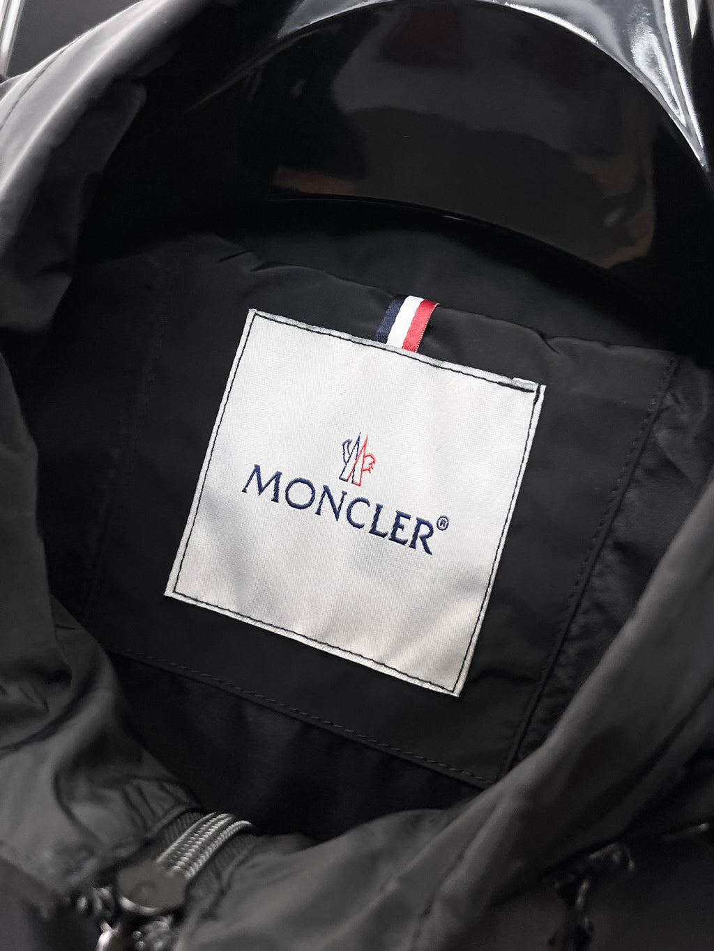 Moncler logo patch on jacket lining with dark quilted texture