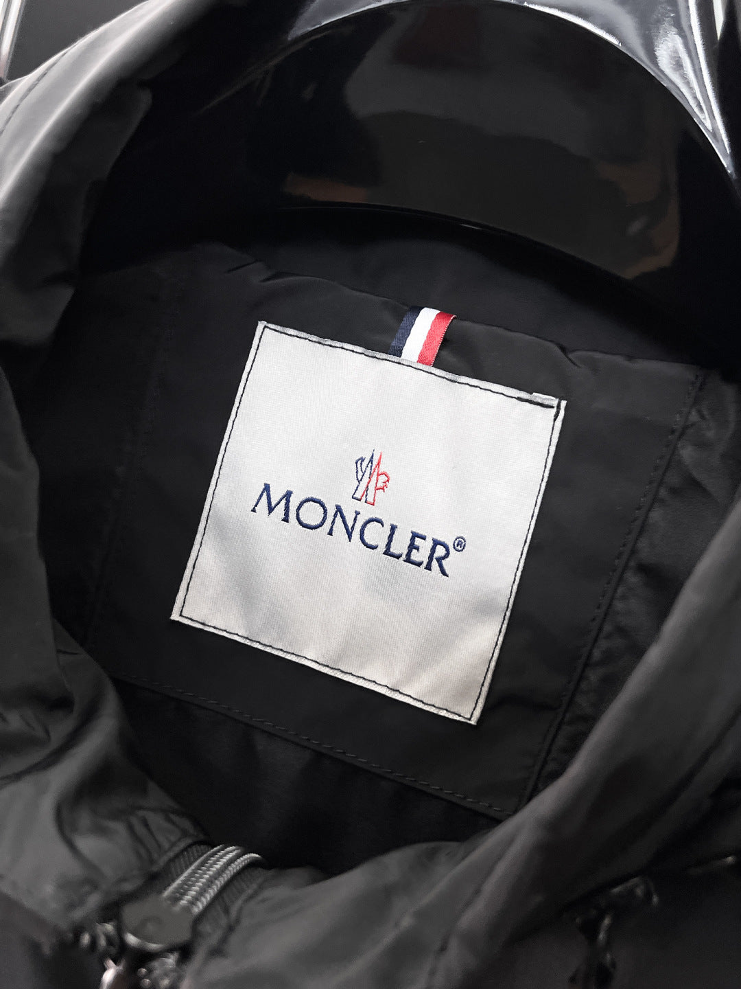 Moncler logo patch on jacket lining with dark quilted texture