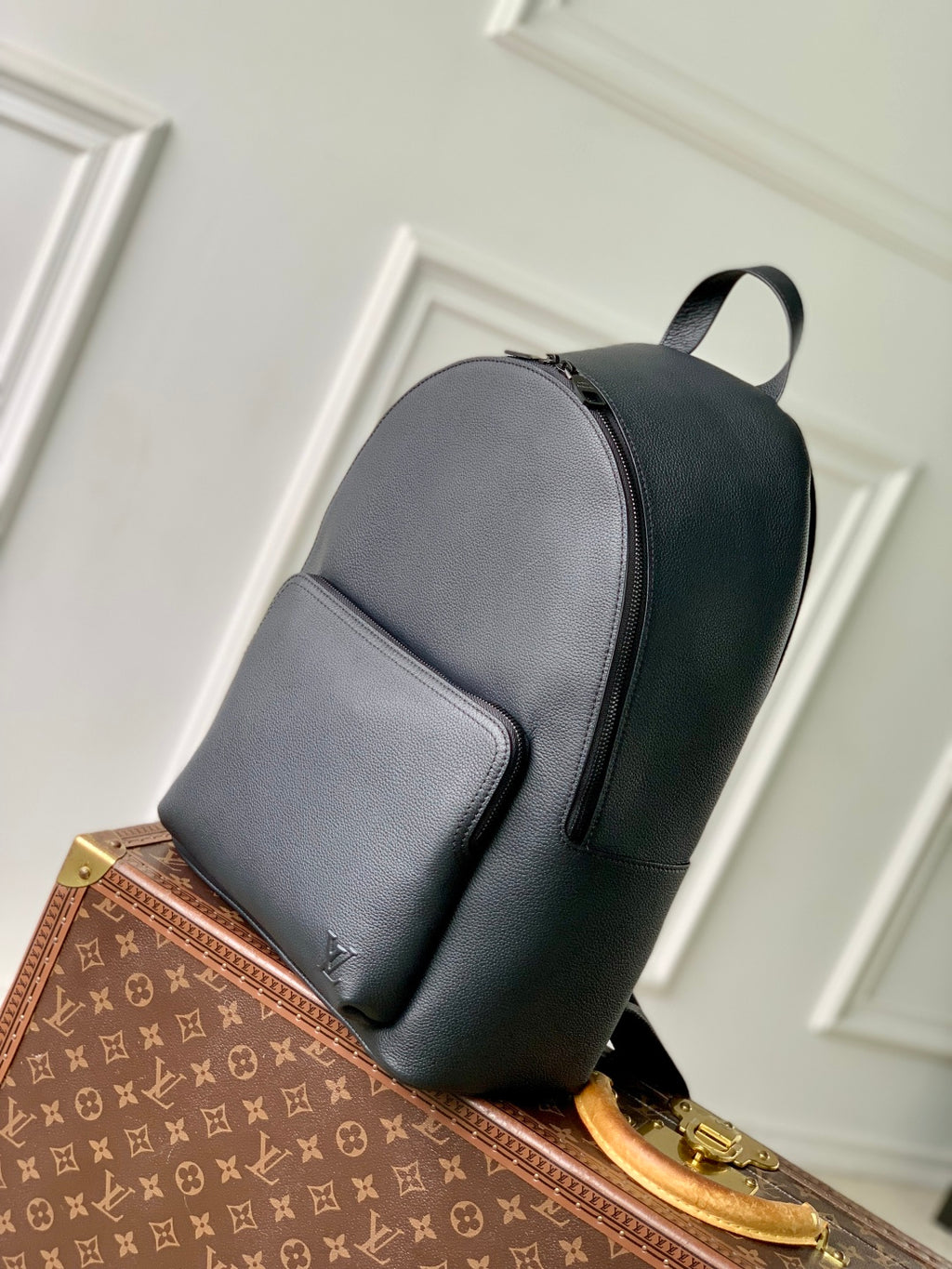 Men's Louis Vuitton leather backpack in dark gray, angled side view with front pocket