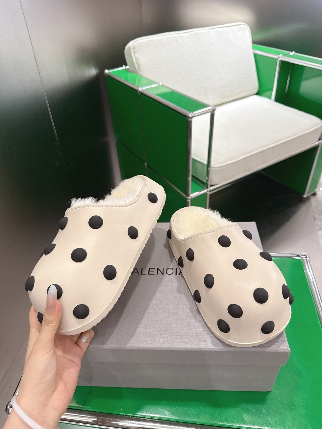 Balenciaga white polka-dot slide sandals, front view with hands holding