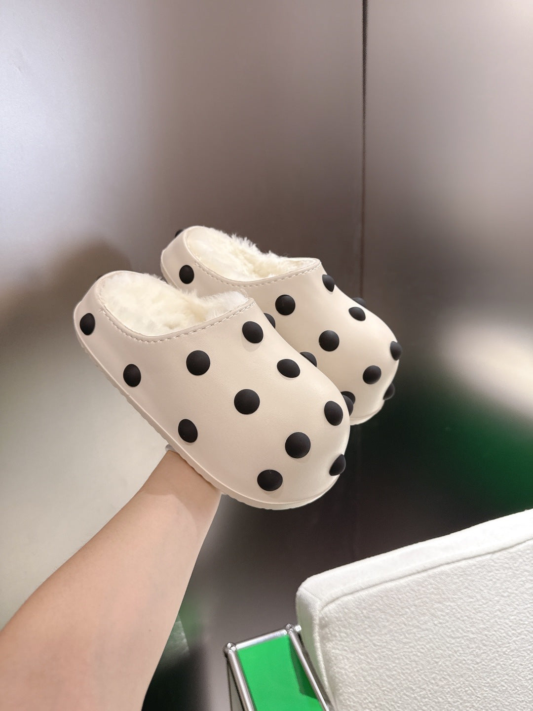 Balenciaga white polka-dot slide sandals with plush lining, hand-held angle