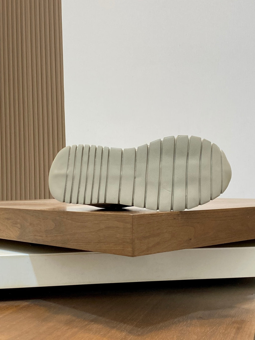 Beige sneaker outsole with textured tread on ridged rubber sole