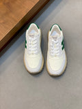 White sneakers with green side panels, lace-up front, rounded toe and low profile