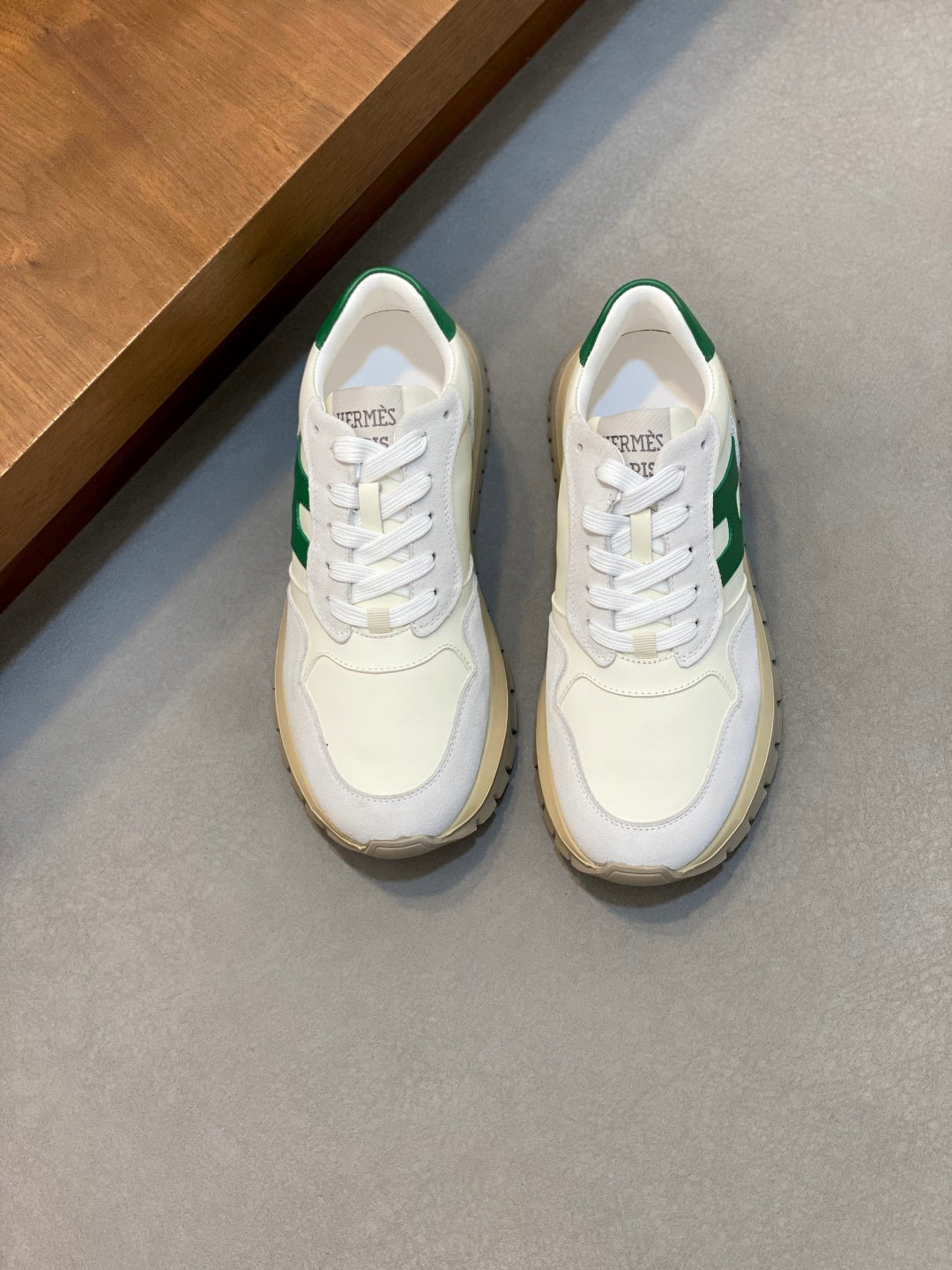 White sneakers with green side panels, lace-up front, rounded toe and low profile