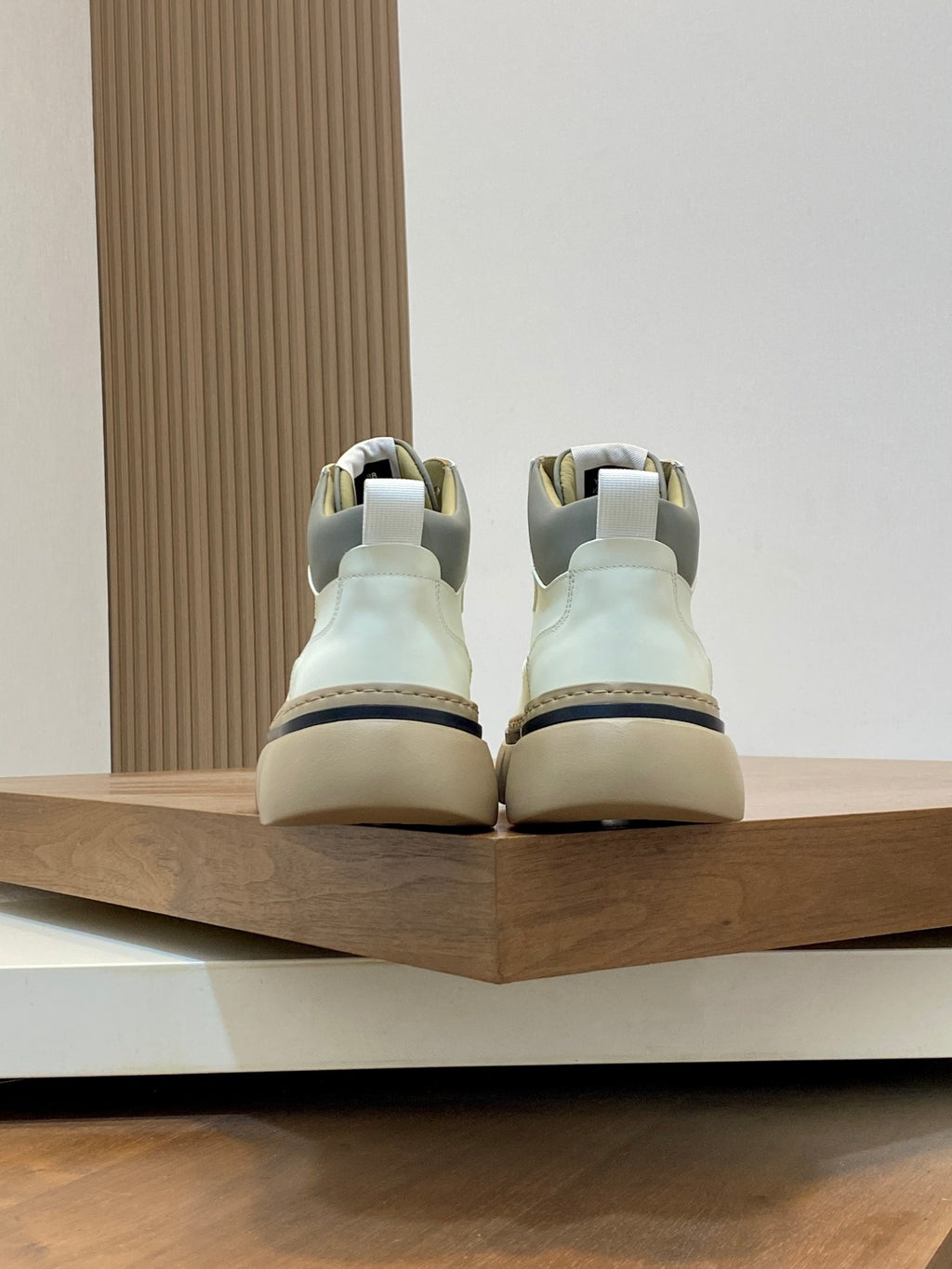 Back view of white lace-up sneakers with dark trim and chunky sole.
