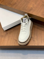 Single white lace-up sneaker with dark trim and beige rubber sole.