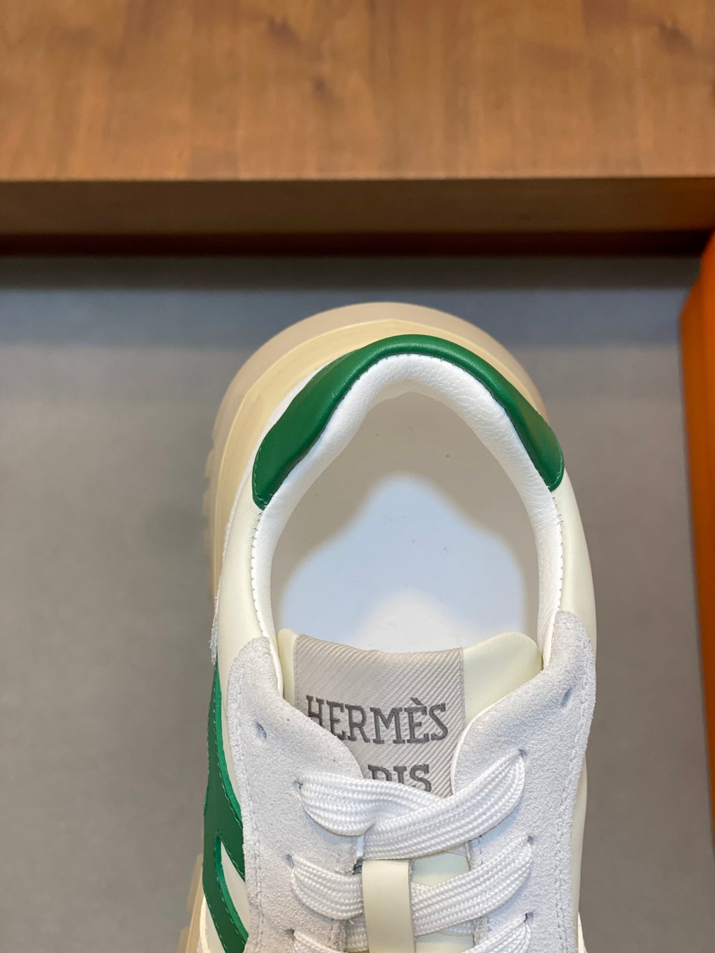 White sneaker tongue with HERMES lettering and green collar trim, close-up