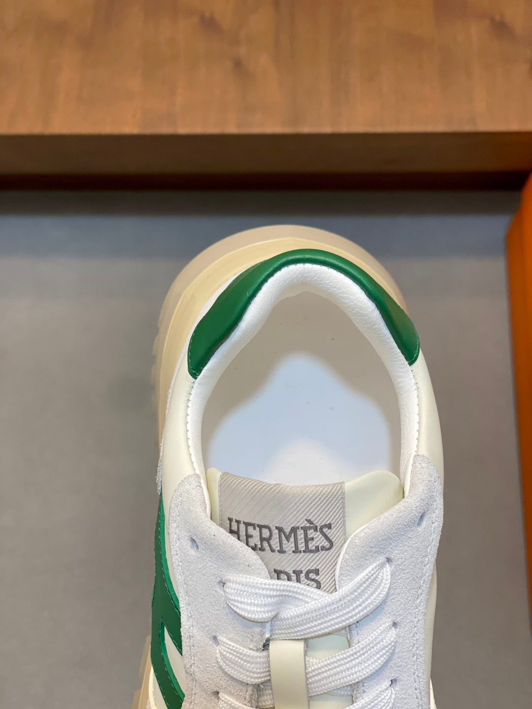 White sneaker tongue with HERMES lettering and green collar trim, close-up