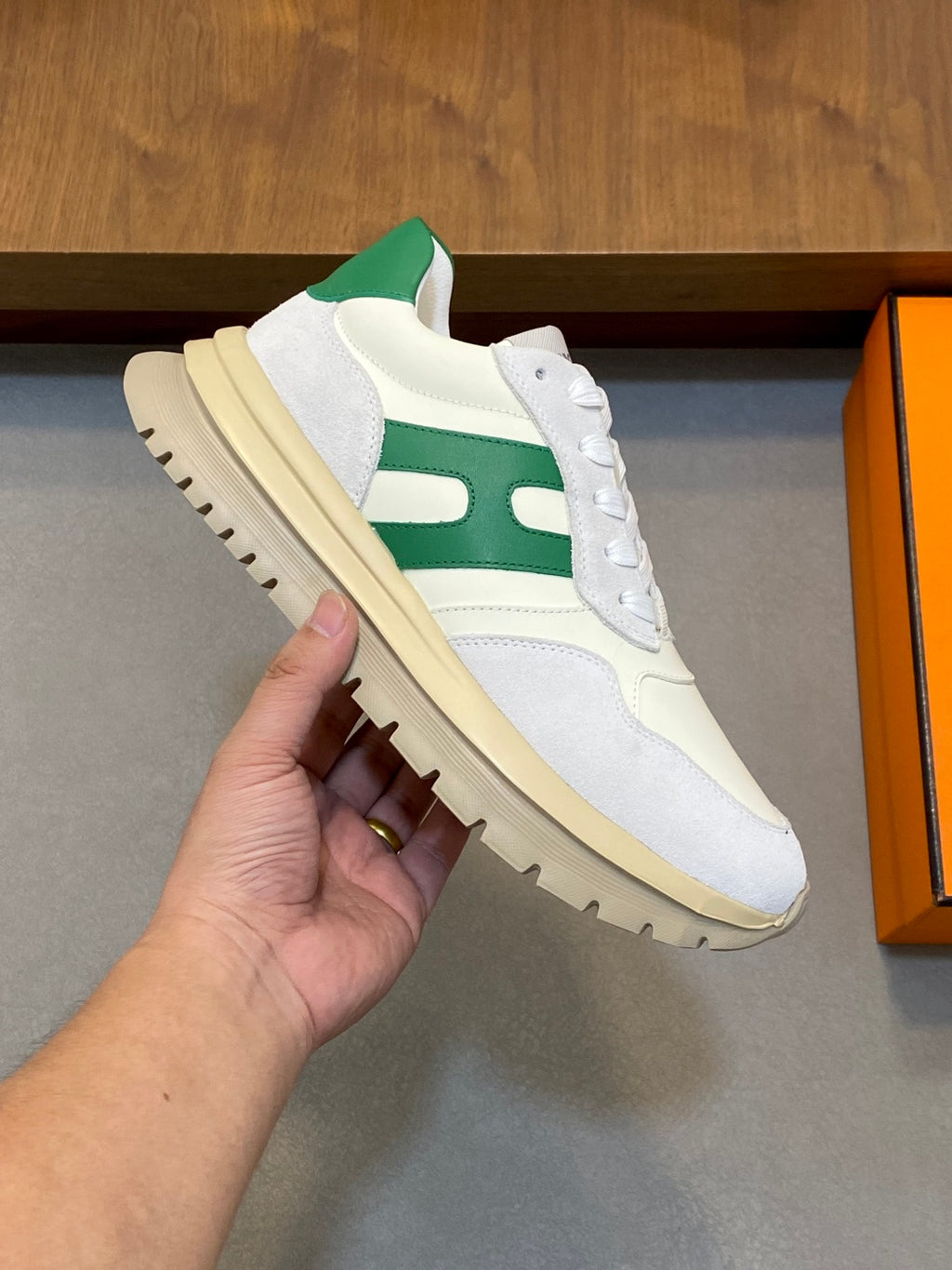 White sneaker with green stripe and thick sole, close-up side view held in hand