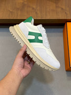 White sneaker with green stripe and thick sole, close-up side view held in hand