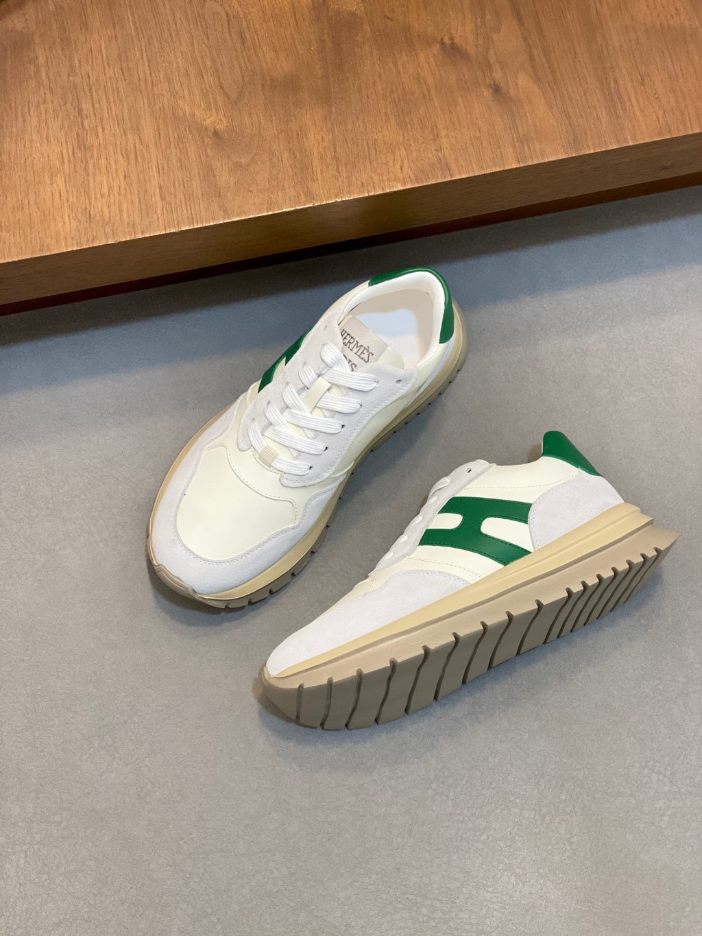 Pair of white sneakers with green side accents, lace-up front and rubber sole