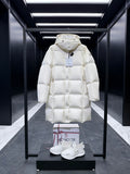 Long quilted puffer coat with hood, light cream, snap-front, long sleeves.