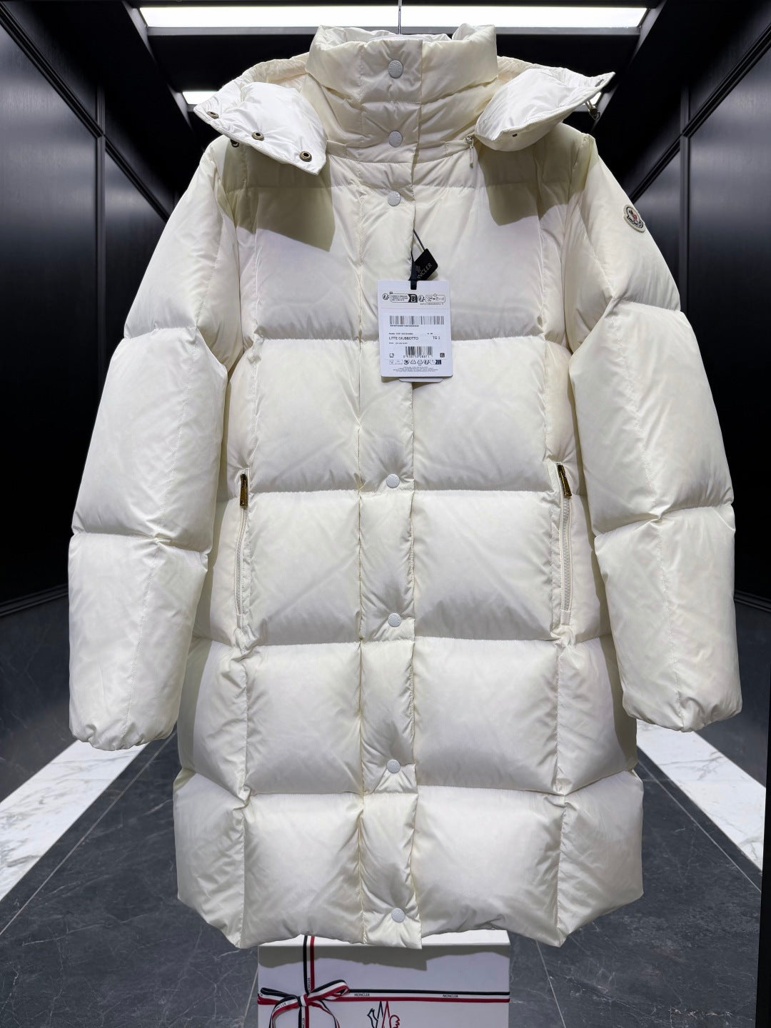 Light cream quilted puffer coat with hood, snap buttons, high collar, long sleeves.