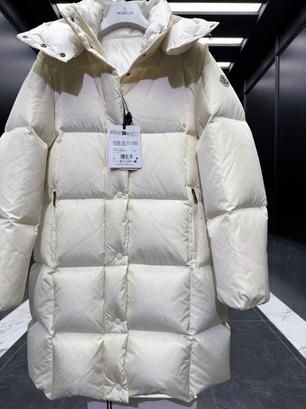 Light cream quilted puffer coat with hood, front placket, diamond stitching, long sleeves.