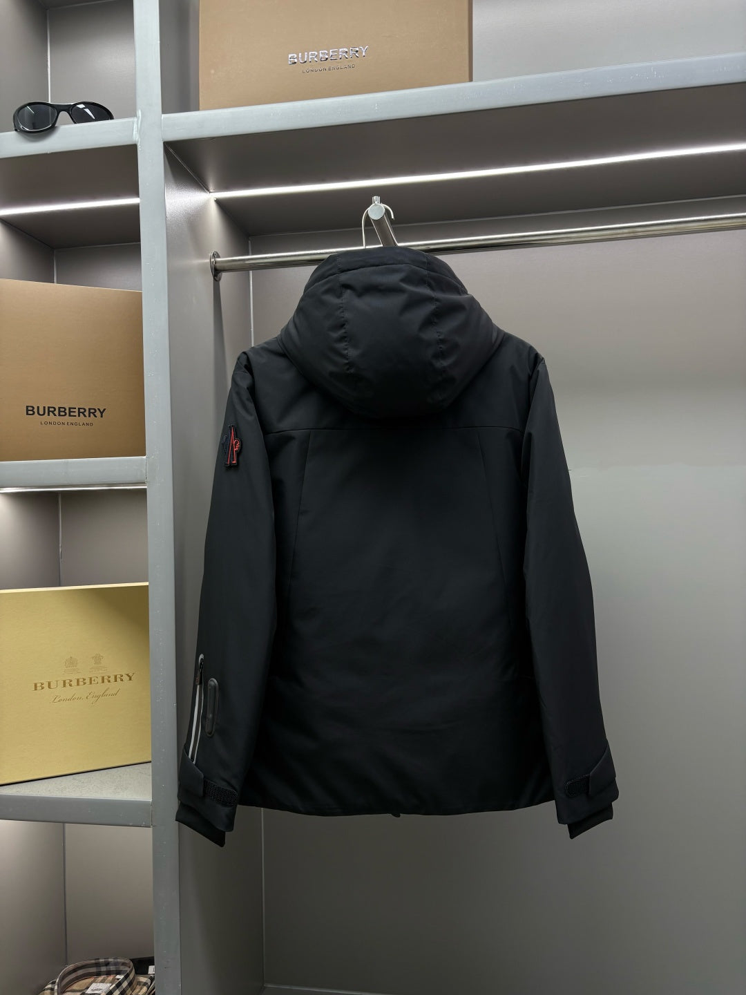 Moncler black long parka back view with attached hood and sleeve zipper pocket