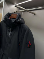 Moncler black long hooded parka with front snap pockets and logo patch