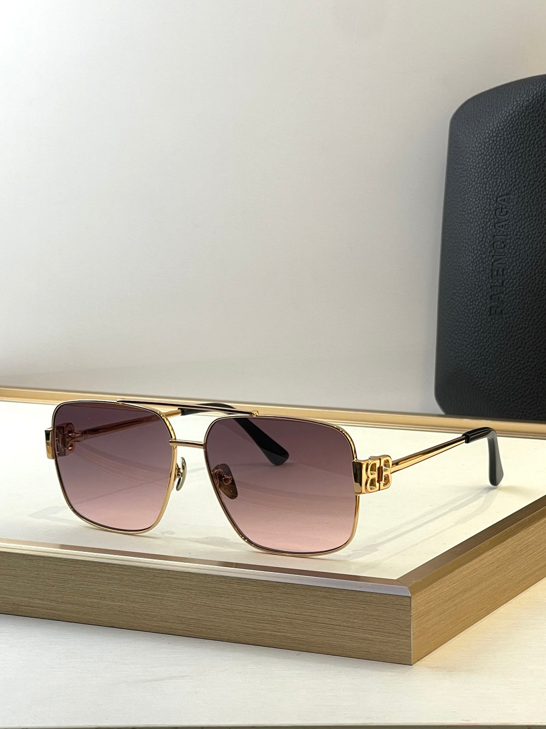 Square gold sunglasses with pink-tinted lenses and black temple tips