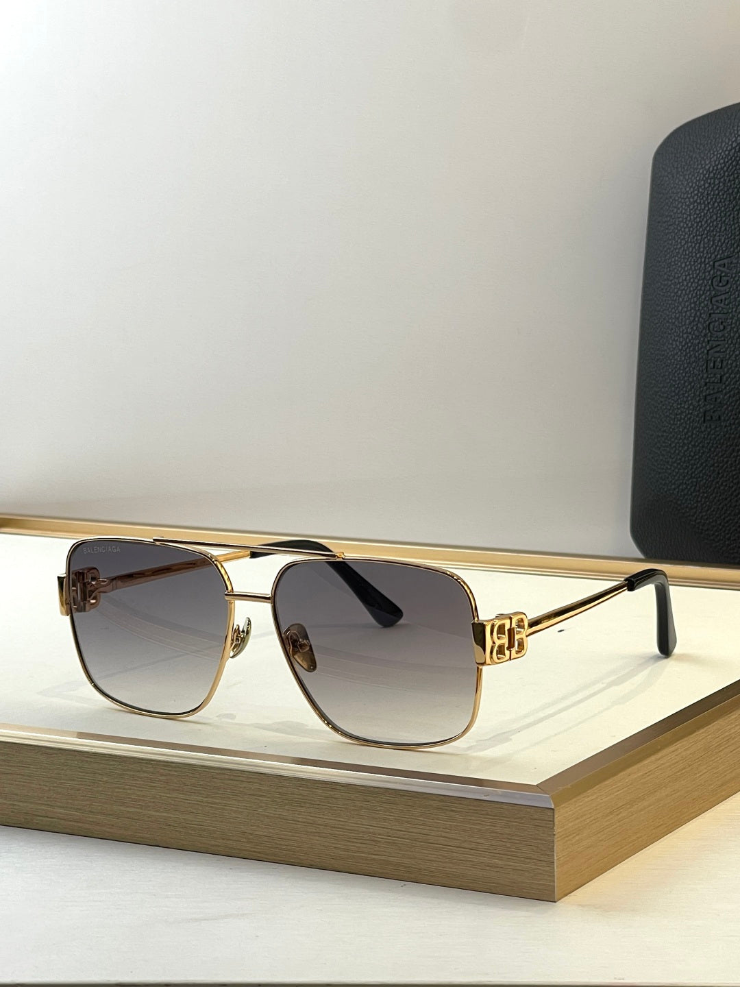 Square gold sunglasses with dark gradient lenses and black temple tips