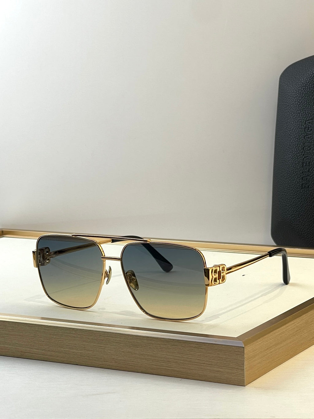 Square gold sunglasses with gray smoke lenses and black temple tips