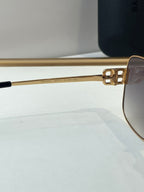 Gold sunglasses close-up of side arm with engraved numbers and dark lens