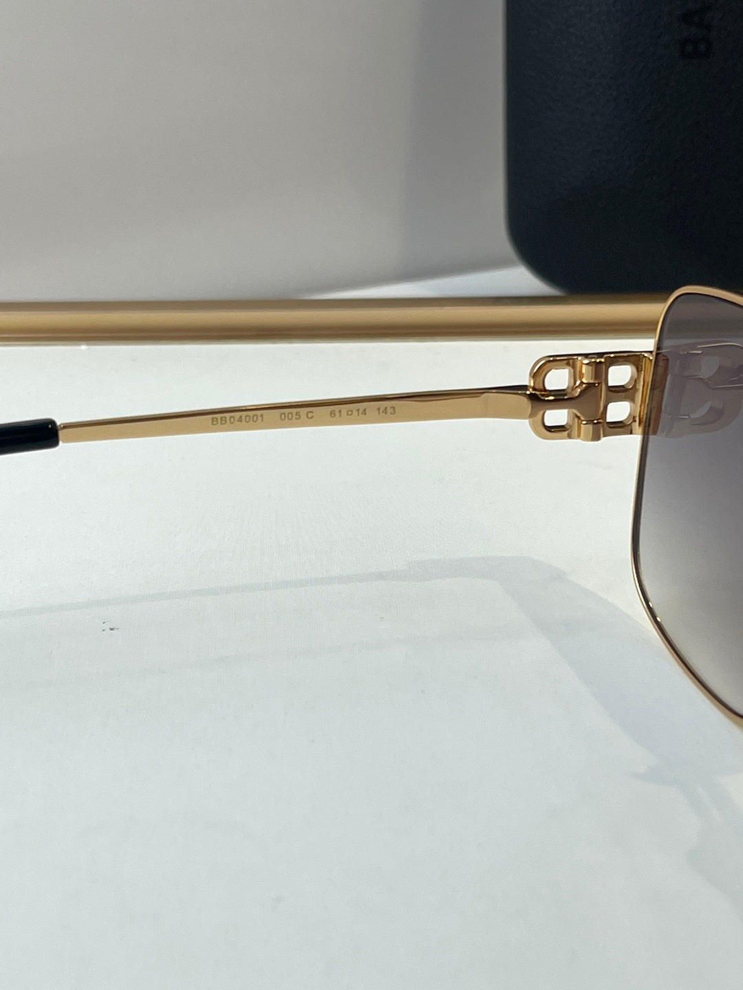 Gold sunglasses close-up of side arm with engraved numbers and dark lens