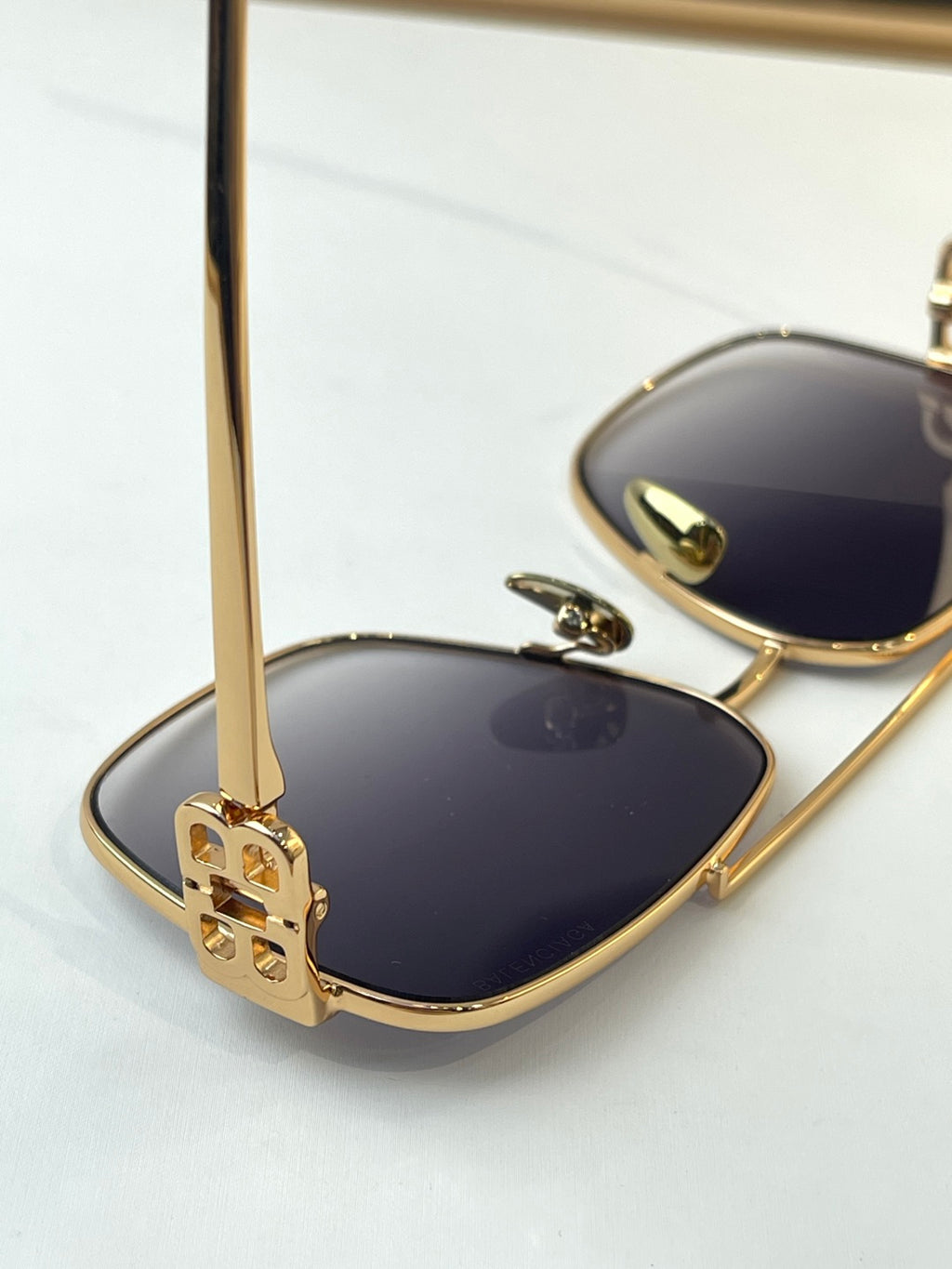 Gold sunglasses close-up with blue lenses and logo temple detail