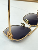 Gold sunglasses close-up with blue lenses and logo temple detail