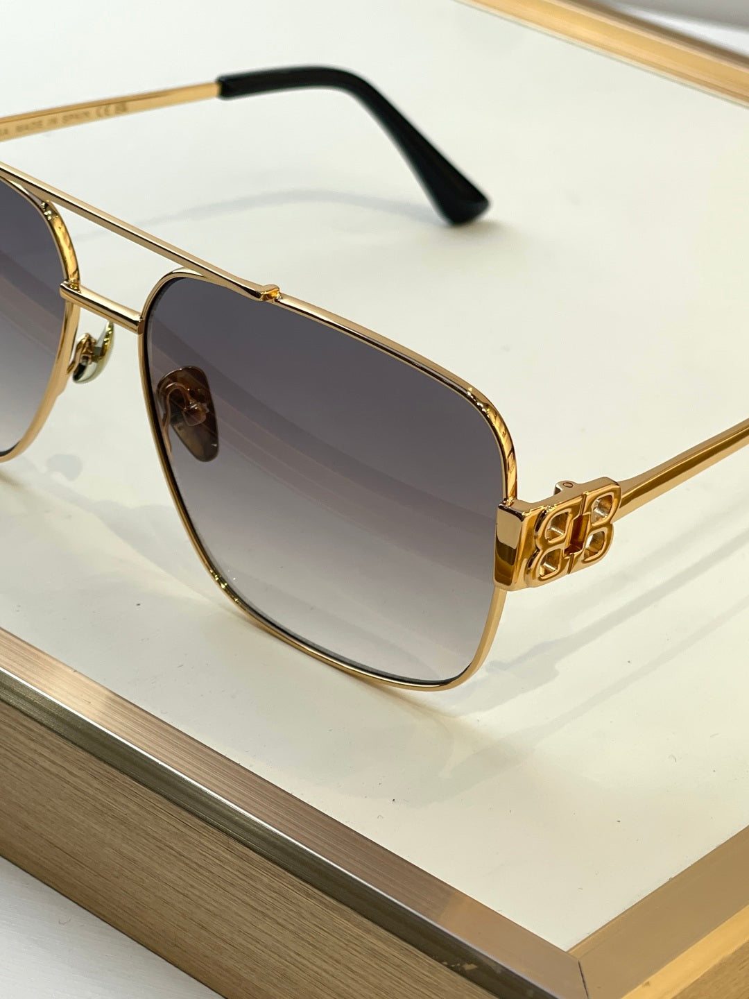 Gold sunglasses close-up with dark lenses and embossed logo detail