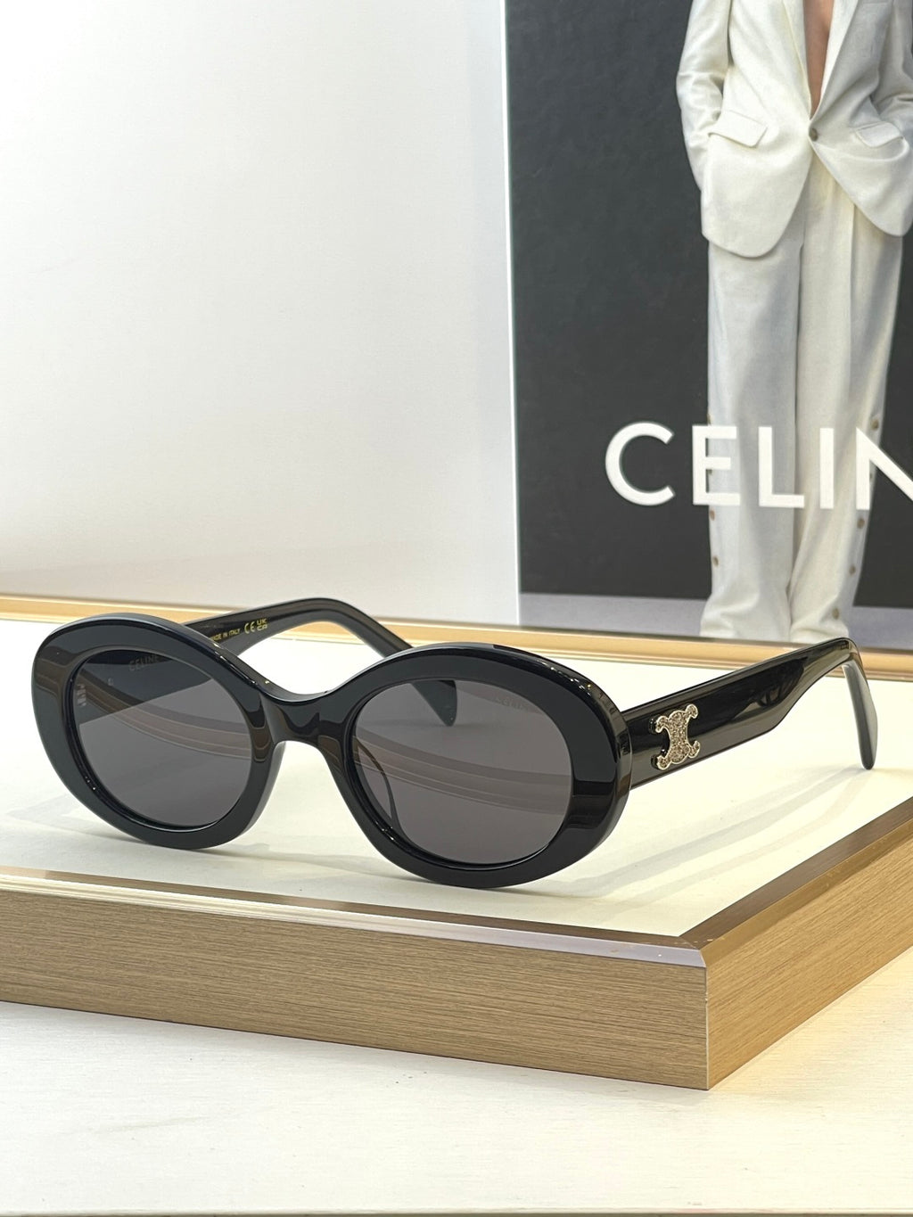 Black round sunglasses with dark lenses and gold temple logo