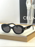 Black round sunglasses with dark lenses and gold temple logo