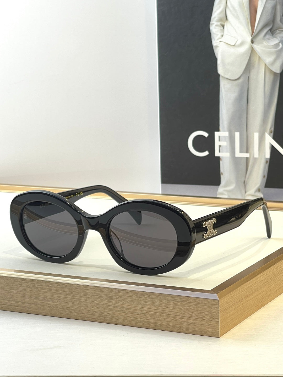 Black round sunglasses with dark lenses and gold temple logo
