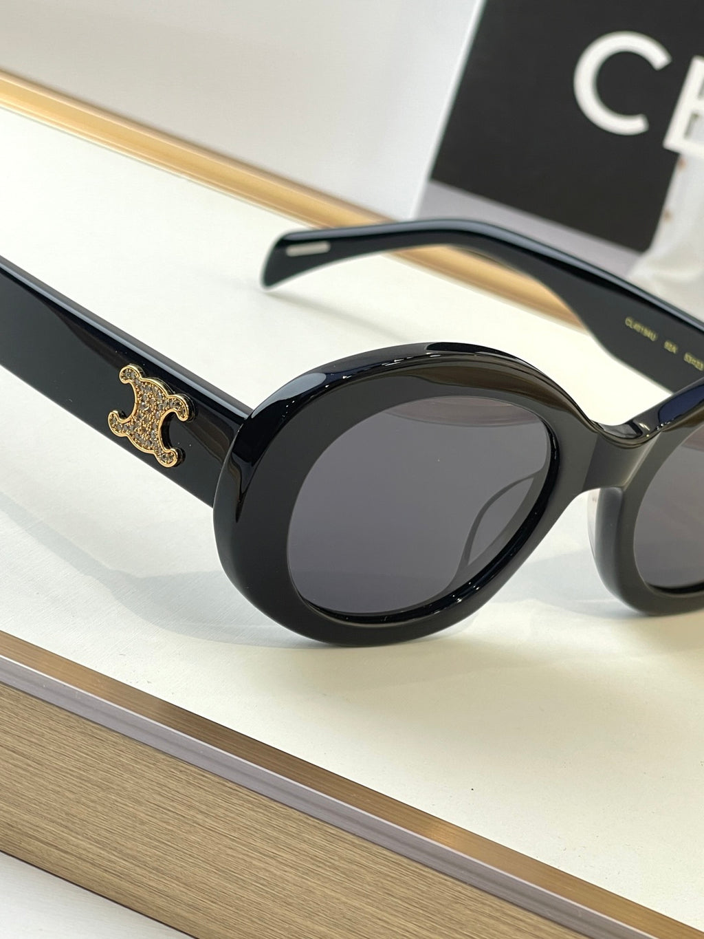 Black oval sunglasses close-up with gold emblem on the temple