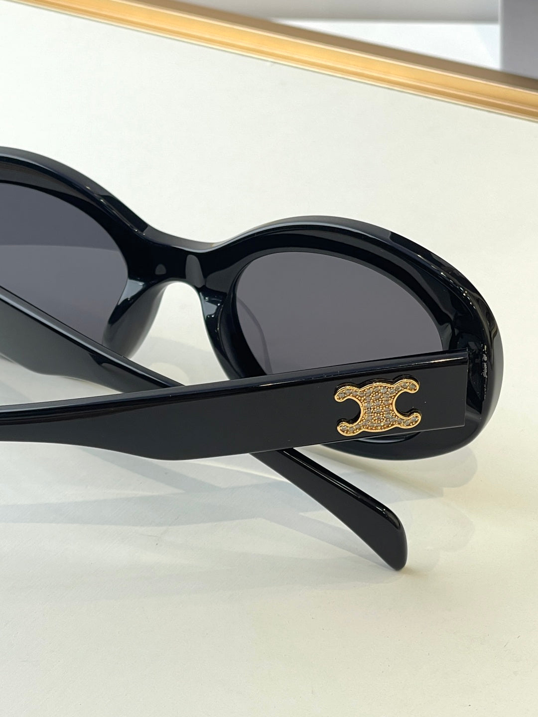 Black sunglasses side view with gold logo on the temple and dark lenses