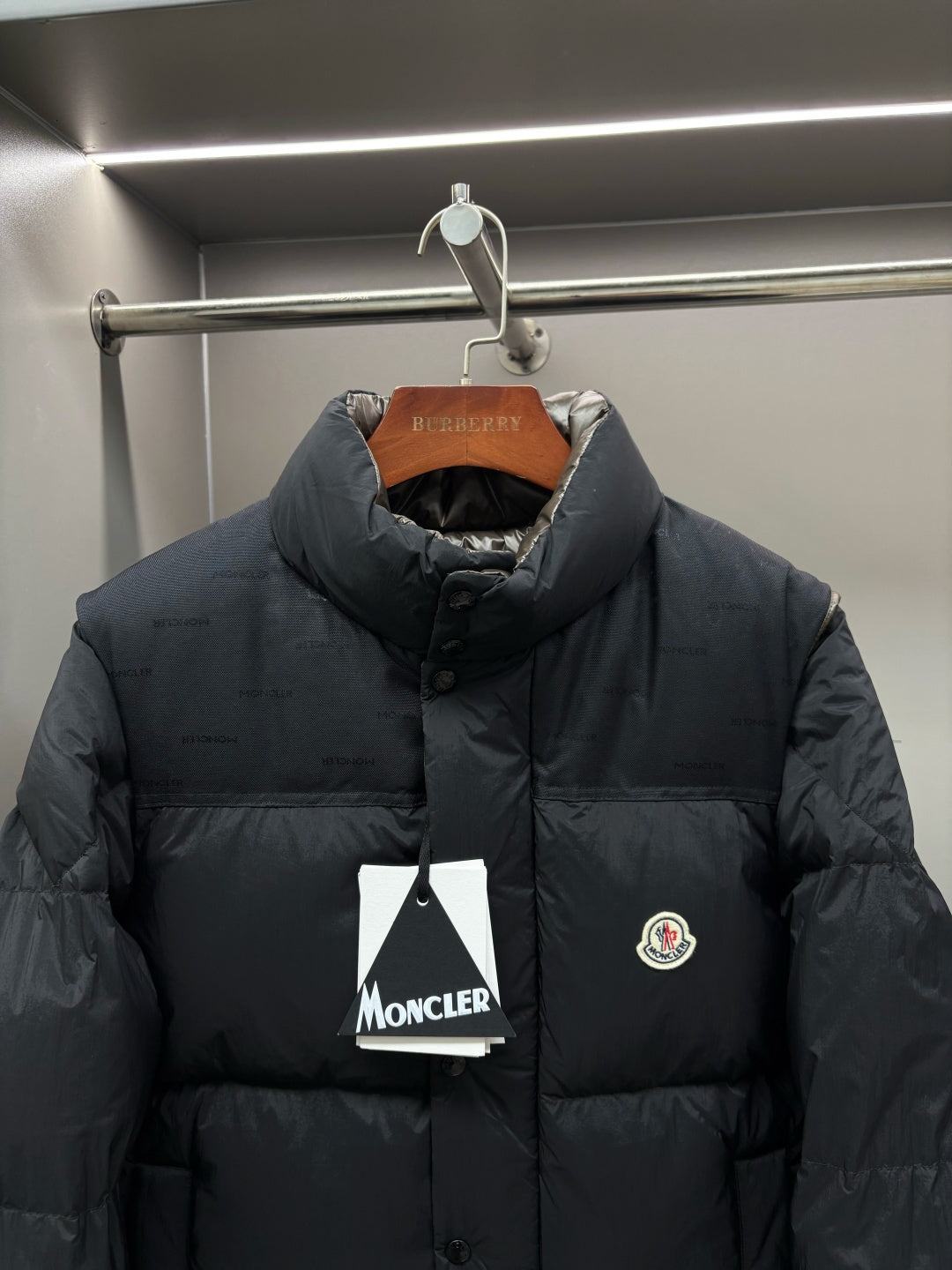 Black puffer jacket with stand collar and full-zip, chest logo patch