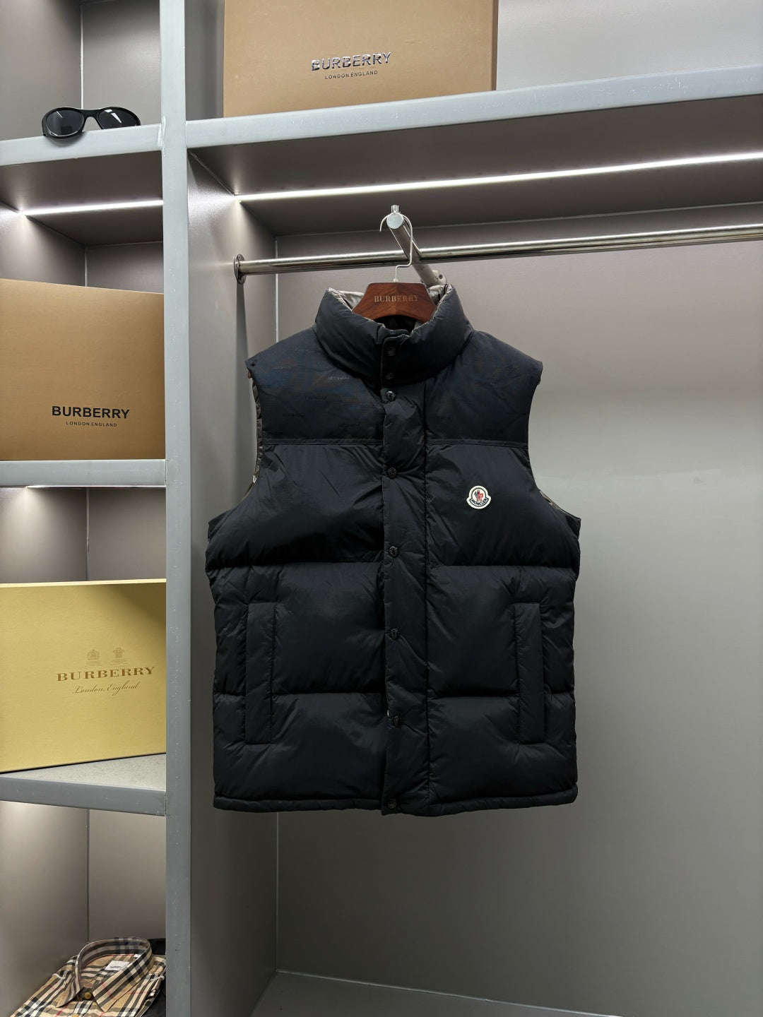 Black quilted puffer vest with button front and high stand collar, logo badge