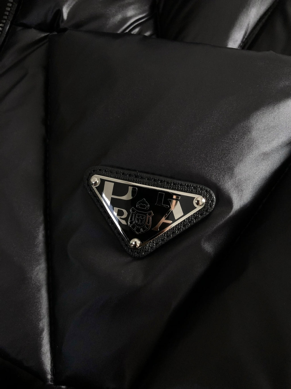Black puffer jacket chest patch with Prada logo and decorative trim