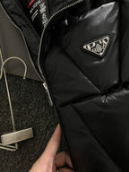 Black puffer jacket close-up with zipper and Prada triangular chest patch