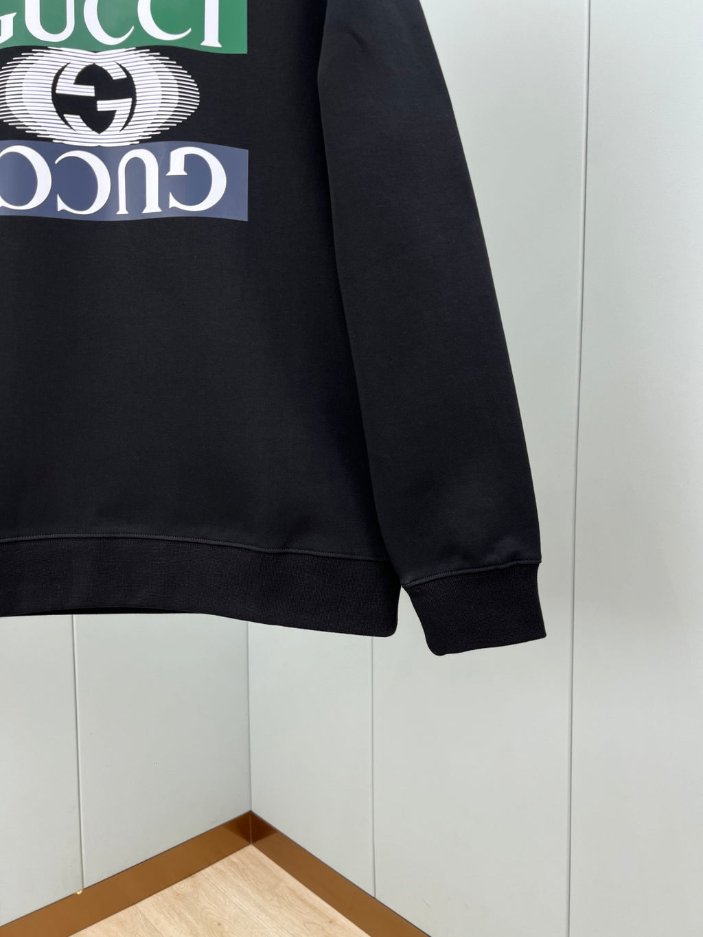 Black crewneck sweatshirt side view with ribbed cuff and front logo