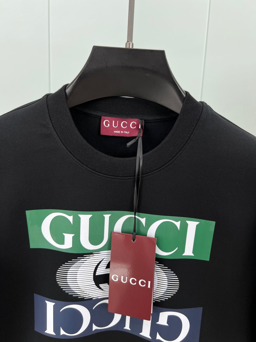 Black crewneck sweatshirt close-up with Gucci logo graphic and red tag