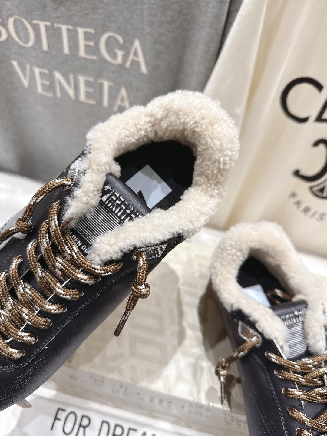 Golden Goose black sneaker close-up: gold lace hardware, fuzzy shearling collar lining