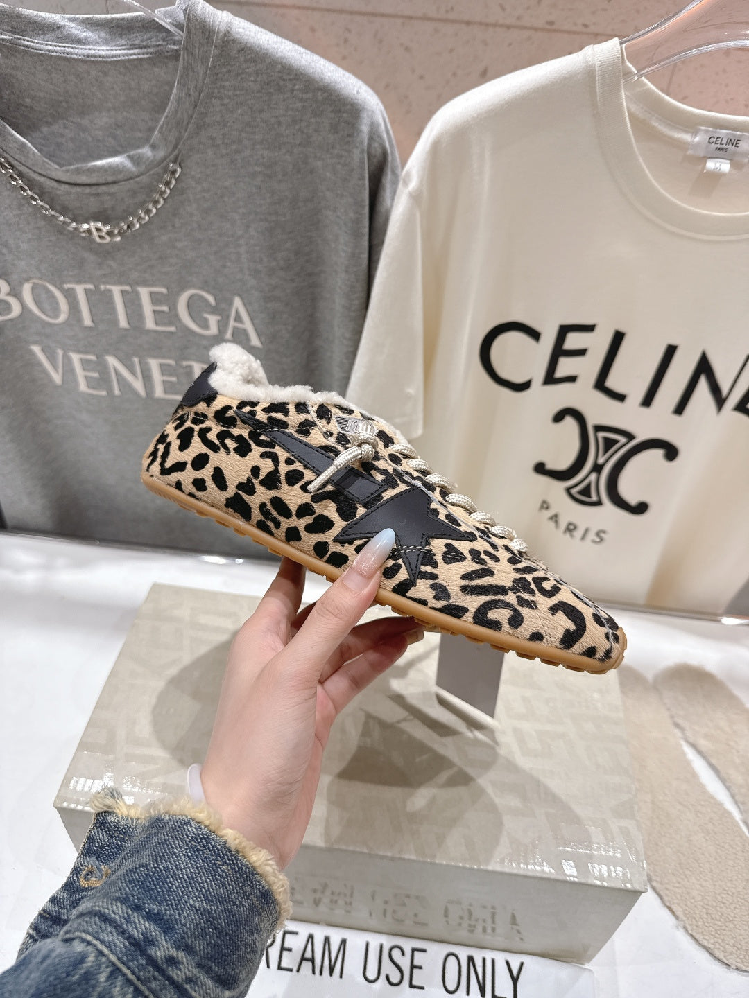 Leopard-print low-top sneakers held in hand, sherpa collar, white lace-up